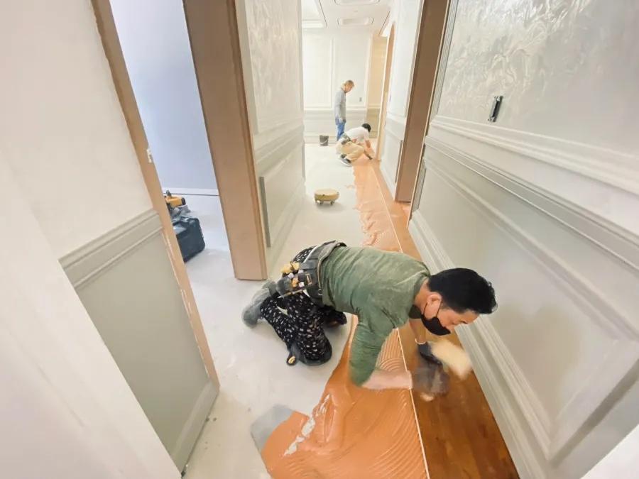 백색 패널 벽면과 대비되는 복도 마루 시공
