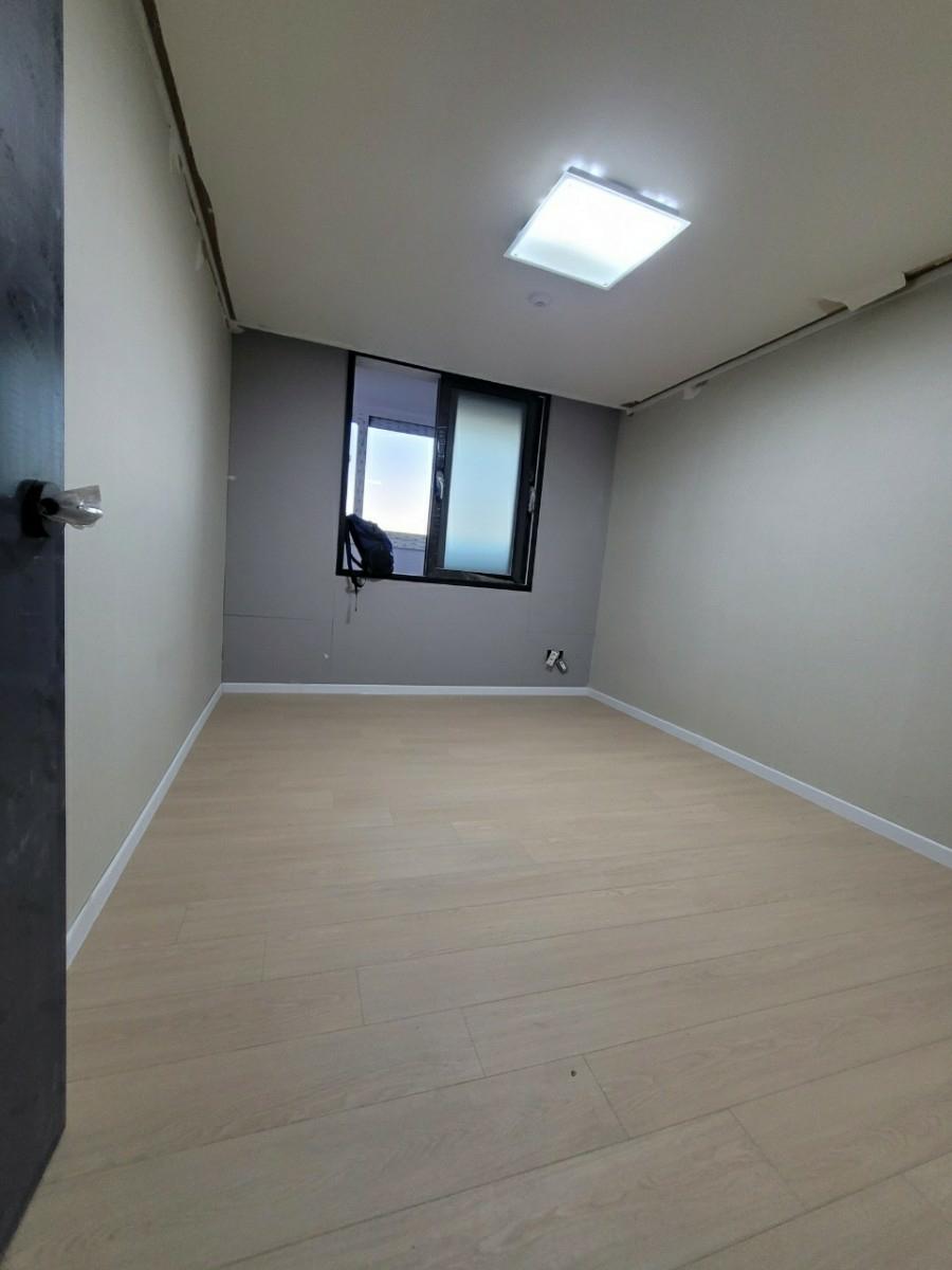 베이지색 바닥재와 검은 테두리 창호가 보이는 방의 모습