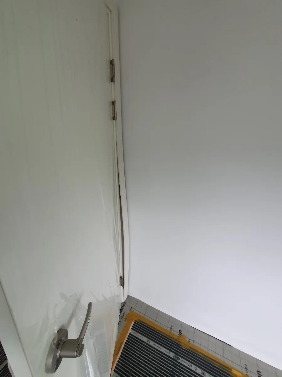 흰색 문의 힌지와 노란색 테이프가 붙은 바닥
