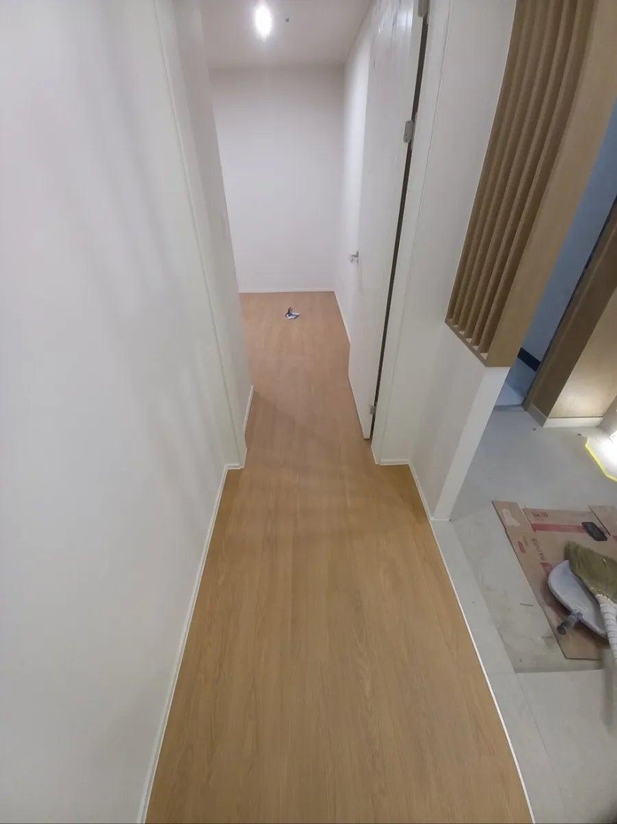 브라운 패널과 우드 바닥이 어우러진 복도 라인