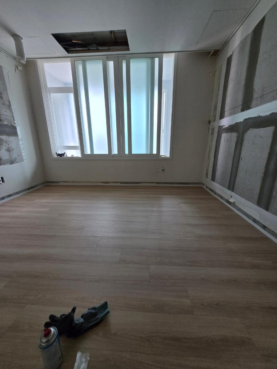 도배 작업과 마루 마감이 동시에 보이는 장면