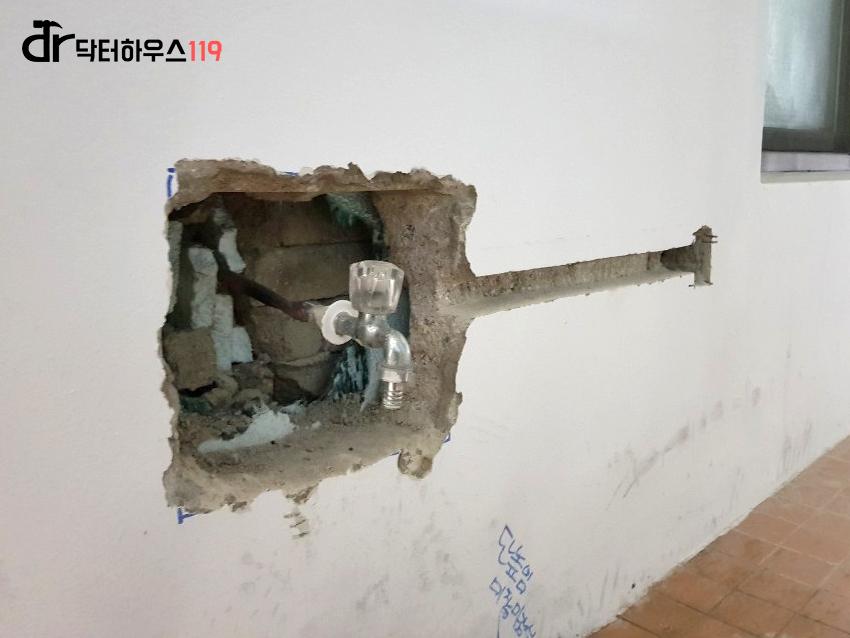 벽면 구멍 사이로 노출된 수도관과 수전