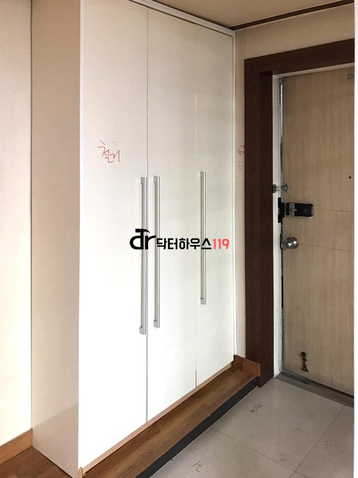 흰색 수납장과 나무 톤 문이 있는 현관 공간