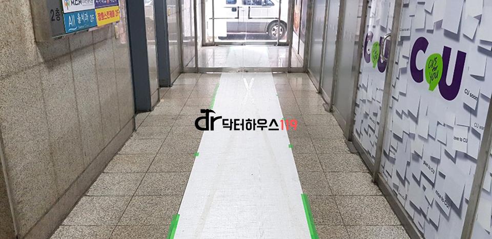 석재 벽면과 흰색 마감 바닥의 복도 모습