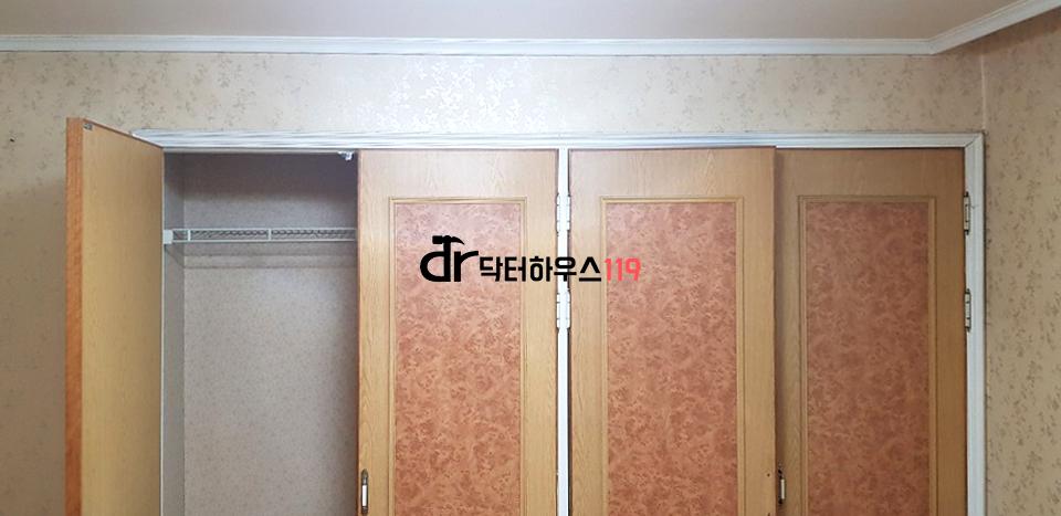베이지색 벽지와 우드톤 수납장이 있는 드레스룸 중문