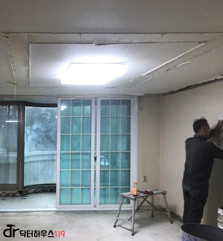 천장 조명 아래 도배 작업이 한창인 실내