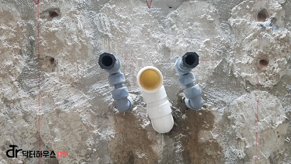 벽면에 설치된 회색 및 흰색 PVC 배관들