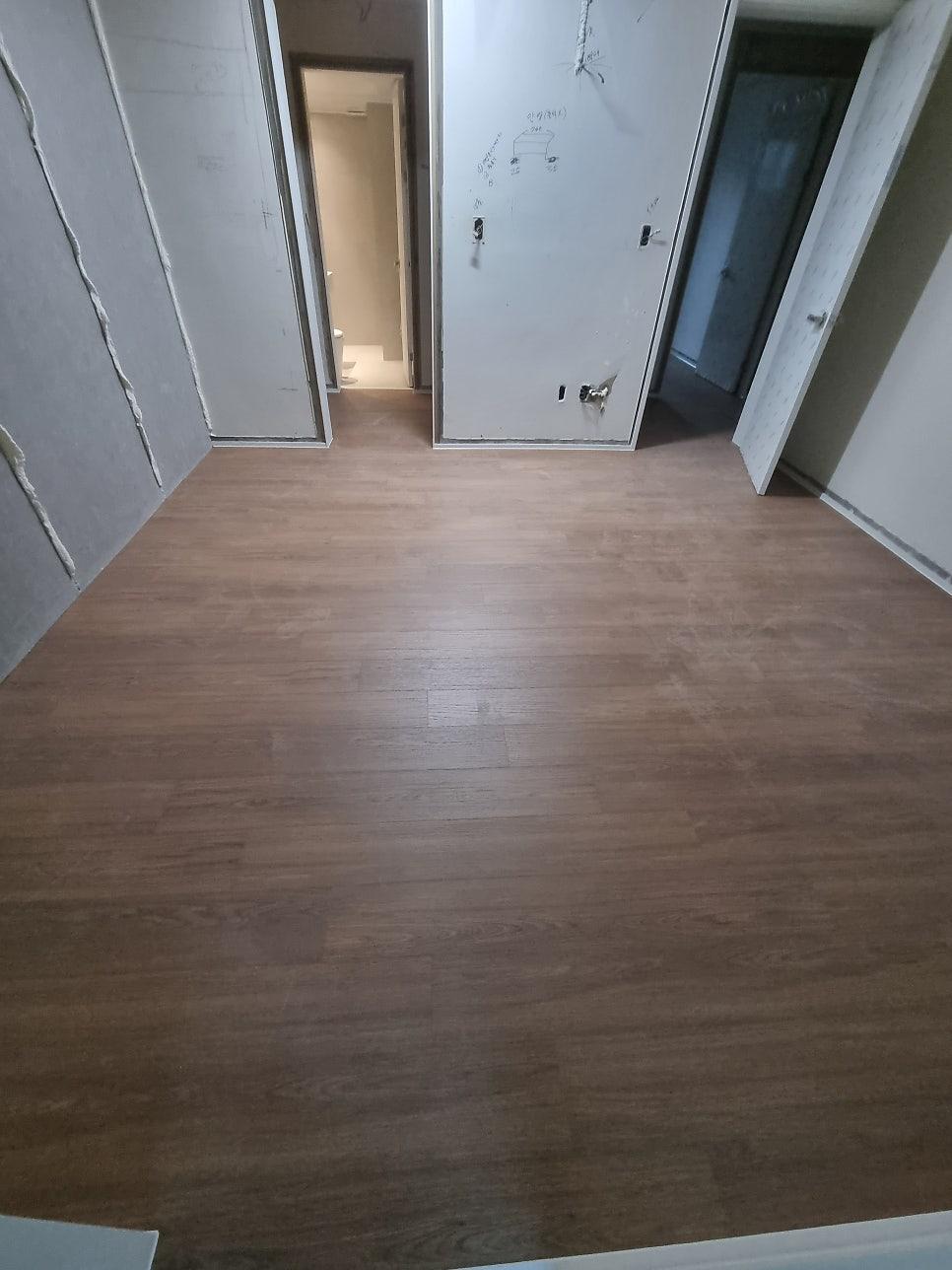 흰 벽지와 나무 바닥이 만나는 복도