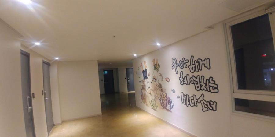 벽화와 한글 문구가 그려진 목재 마감 복도