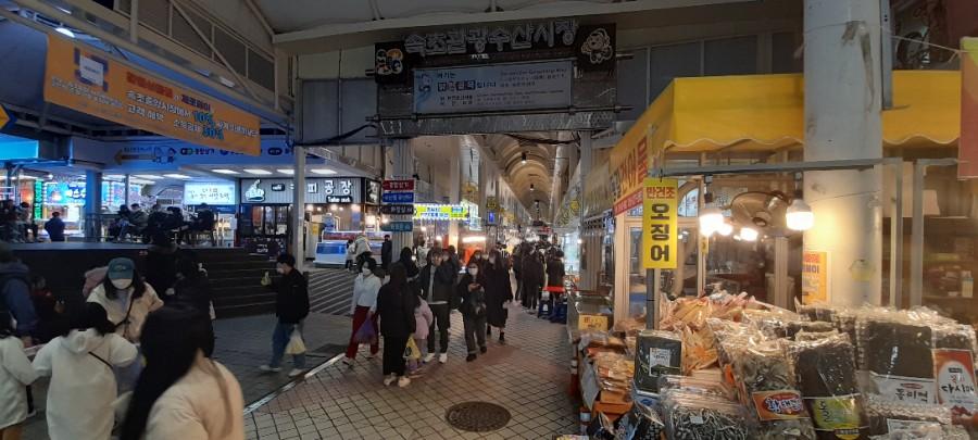 다양한 간판과 사람들로 붐비는 시장 통로