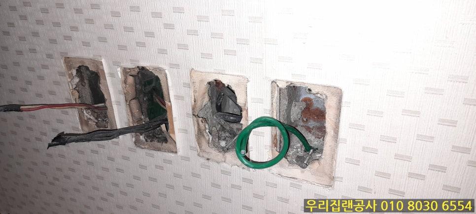 벽지가 제거된 상태에서 보이는 빨간색, 검은색, 녹색 전선