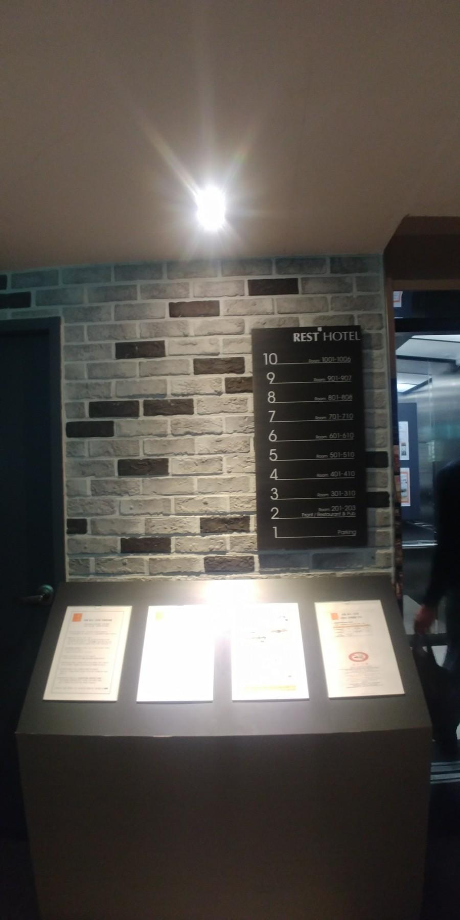 벽돌 벽면에 부착된 REST HOTEL 표시판과 정보 테이블