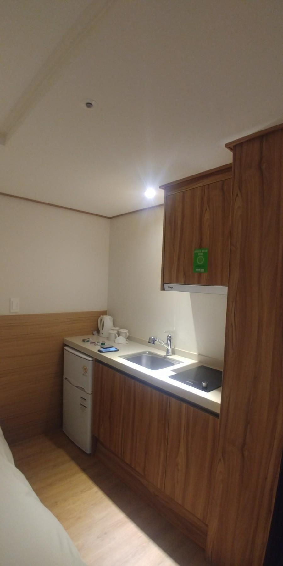 목재 패널과 밝은 색 석재 상판이 적용된 주방 공간
