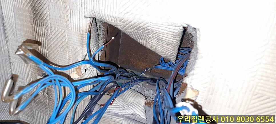벽 구멍으로 노출된 파란색 전선과 금속 부품