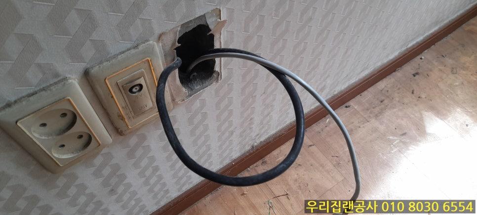 전기 소켓 주변의 파손된 구멍과 검은색 케이블
