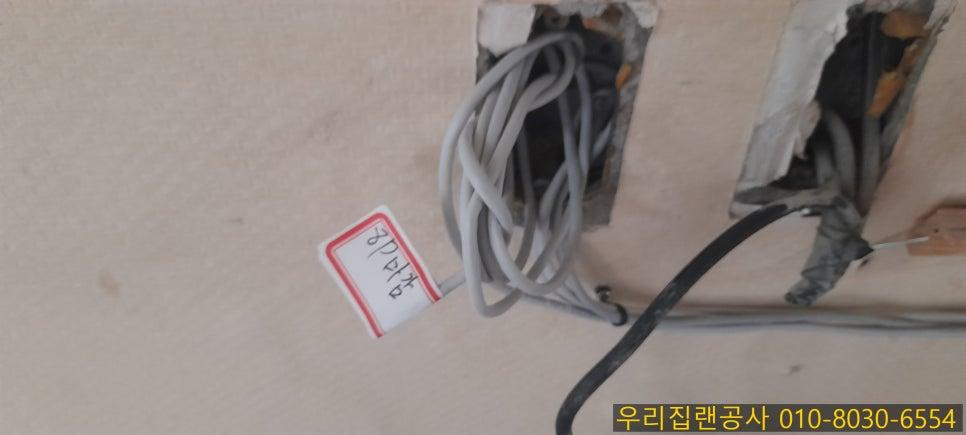 회색·검은색 전선과 흰색 라벨이 보이는 벽 구멍