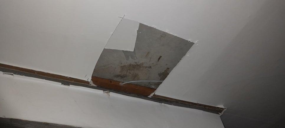 마감재가 제거되어 콘크리트와 나무 보드가 노출된 벽면
