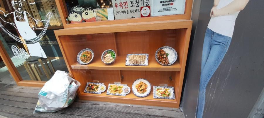 나무 선반 위에 진열된 음식 사진과 인물 일러스트가 있는 벽면