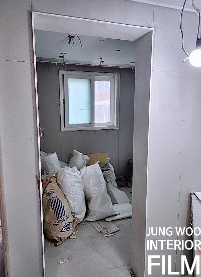 자재가 쌓여 있고 천장 전선이 노출된 마감 전 실내