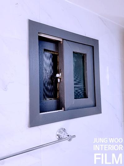 흰 타일 벽과 대비되는 회색 프레임 창호