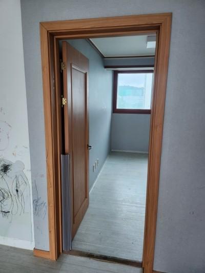 회색 타일 바닥과 나무 재질 여닫이문이 있는 복도
