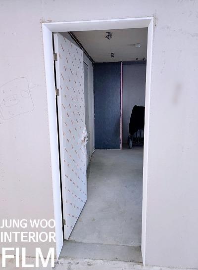 회색 콘크리트 바닥과 흰색 문틀이 보이는 복도 전경