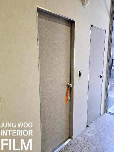 베이지색 마감 도어와 주황색 보양 테이프가 보이는 복도