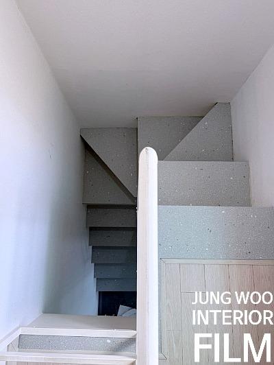 흰 벽면과 평면적인 회색 계단이 보이는 공간