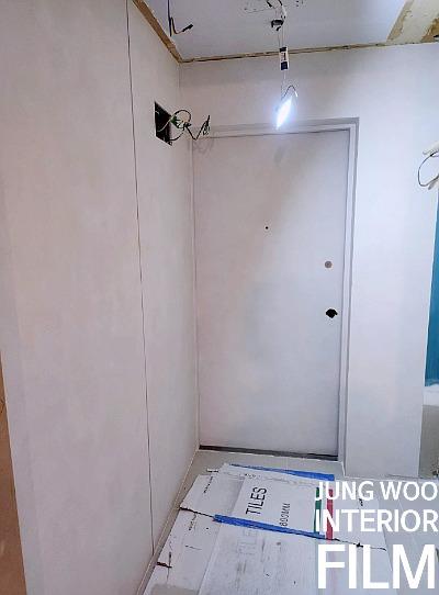 전선이 노출된 상태의 흰 벽과 도어가 있는 현관