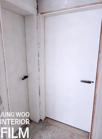 흰 벽과 대비되는 검은 손잡이의 도어