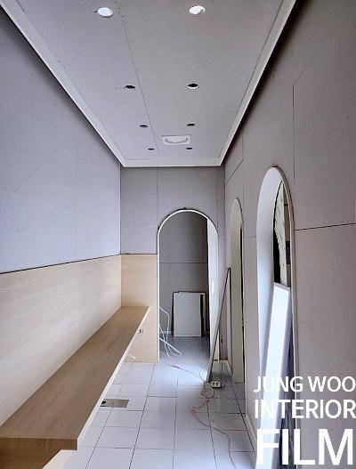 상하단 색상이 구분된 벽면과 아치형 문이 보이는 복도