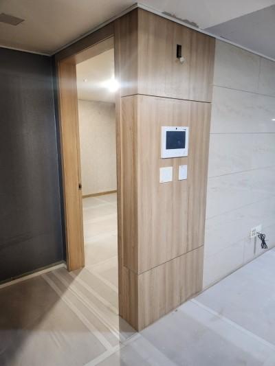 우드톤 벽면과 흰색 타일 바닥이 보이는 현관