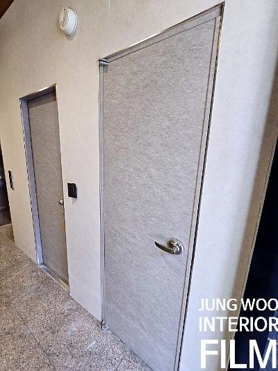 회색 텍스처 문짝과 금속 재질 문틀이 설치된 벽면