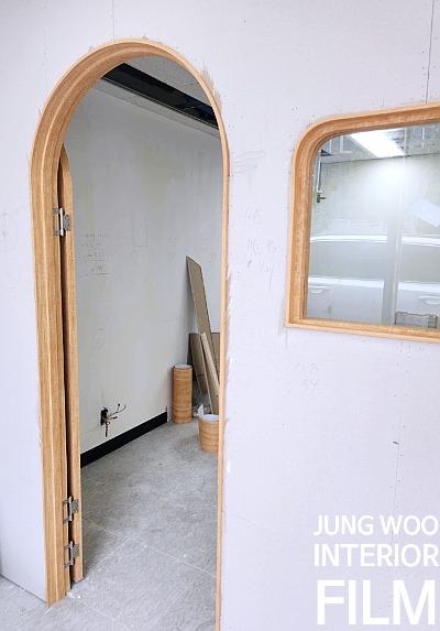 흰 벽면의 목재 아치형 문과 사각형 창호