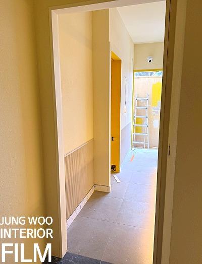 베이지색 톤의 벽면과 노란색 문틀이 보이는 복도