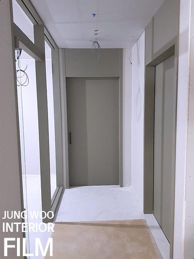 회색 도어와 슬라이딩 창호가 설치된 작업 중인 공간