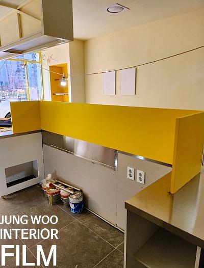 노란색 상판과 회색 타일이 시공 중인 주방 모습
