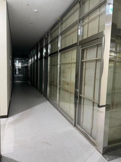 밝은 타일 바닥과 유리문이 배치된 복도