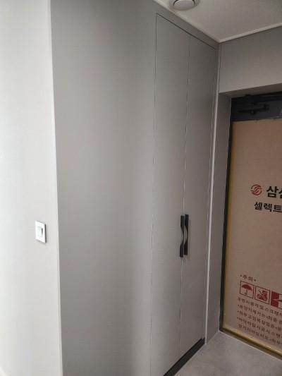 회색 수납장과 보호 테이프가 보이는 현관 시공 전 모습