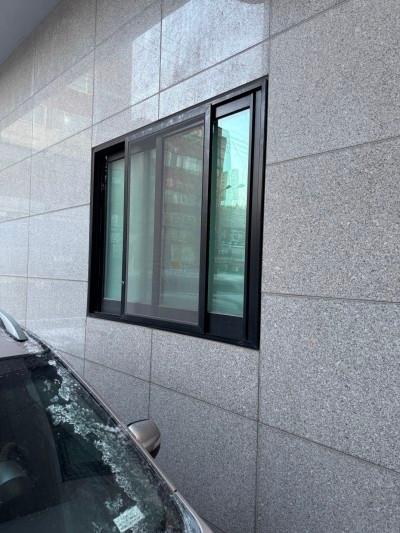 회색 석재 벽면과 검은 창호 프레임