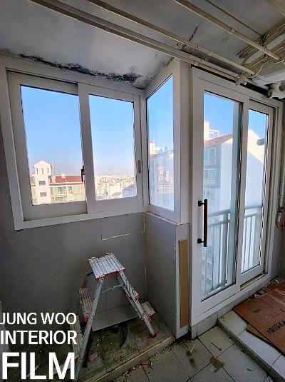 접이식 사다리가 놓인 발코니의 흰색 프레임 창호