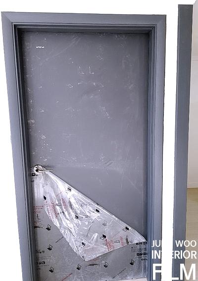 보호 필름이 부착된 문틀과 회색 문짝의 마감 과정