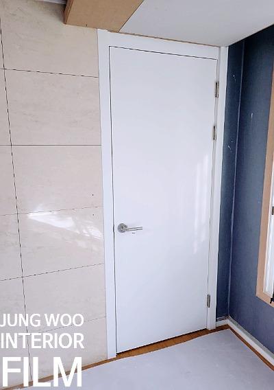 베이지 타일과 파란 벽면이 맞닿은 도어 근접 샷