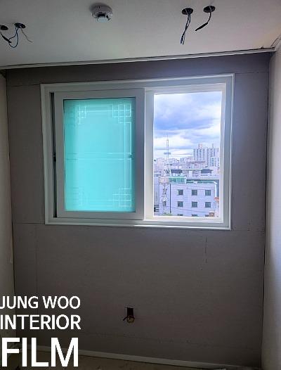 회색 벽지와 푸른색 보호 필름이 보이는 창호