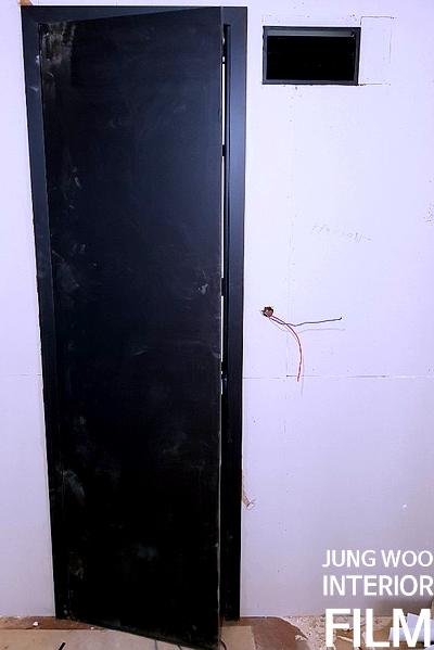 흰 벽에 설치된 검은색 문과 노출 전선