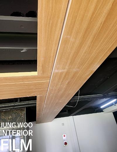 나무 수납장과 천정 조명 구조물이 보이는 공간