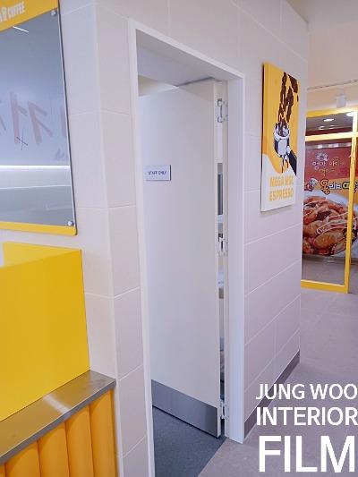 흰 벽돌 벽과 노란색 포스터가 배치된 내부 공간