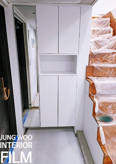 흰색 수납장과 플라스틱 보호재가 설치된 현관