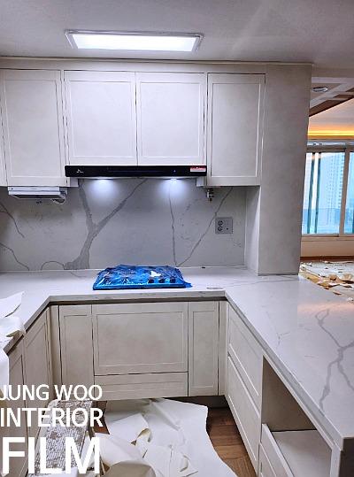 블랙 레인지후드와 흰색 수납장이 배치된 벽면