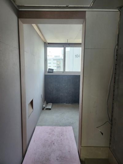 흰색 타일 바닥과 창문 아래 검은색 마감이 보이는 복도